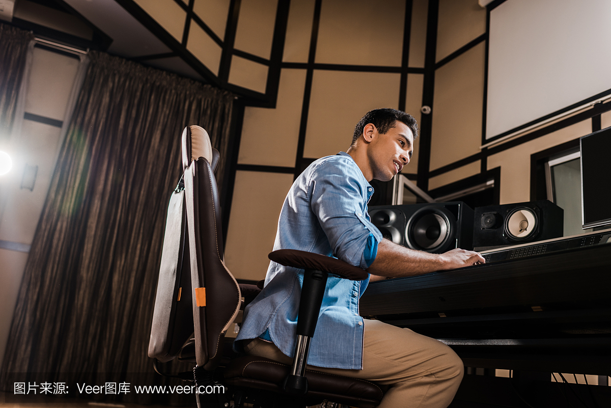 英俊的混合種族聲音制作人在錄音室混音控制臺工作
